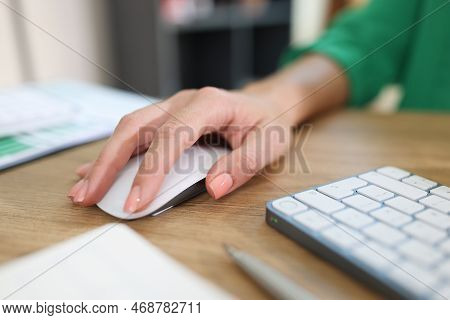 Close-up Of Business Womans Hand Holding Computer Mouse On Office Desk With Keyboard And Documents. 