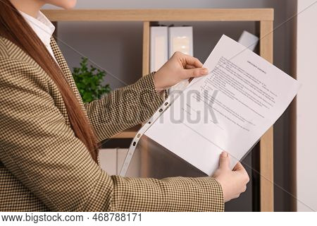 Businesswoman Putting Document Into Punched Pocket In Office, Closeup