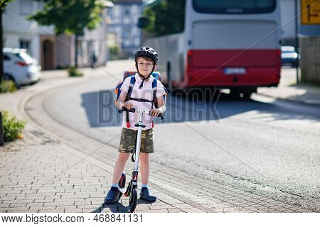 Active School Kid Boy With Glasses In Safety Helmet Riding With His Scooter In The City With Backpac