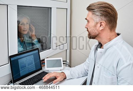 Audiologist Doing Hearing Test To Mature Female Patient In Soundproof Audiometric Booth With Audiome