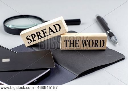 Spread The Word Text On A Wooden Block On Black Notebook , Business Concept
