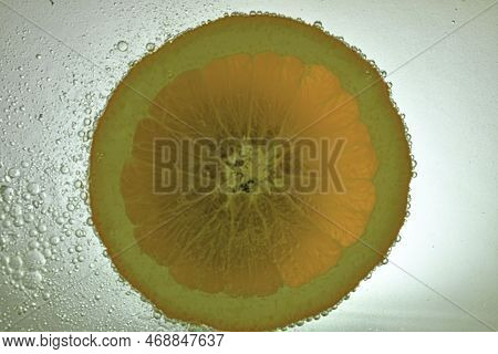 Close-up Of Fresh Orange Slice On White Background. Slice Of Orange In Sparkling Water On White Back