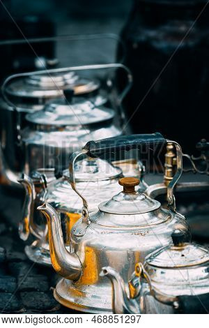 Close Up View On Metal Vintage Tea Pots In A Row At Flea Market. Second Life For Old Things. Old Tab