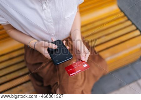 High-angle View Cropped Shot Of Unrecognizable Young Woman Holding Bank Card, Entering Cvv Code Or P