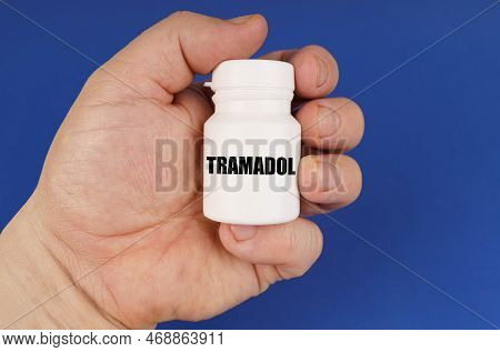 Pharmacology Concept. On A Blue Background In The Hands Of A Man Is A White Jar With The Inscription
