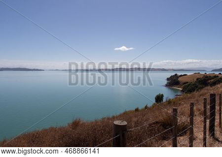 The View Of Picturesque Landscape With Dry Grass Slope, Blue Sea And Mountains On Background In A Su