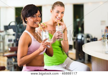 Giovani - donne in palestra bere un frullato bevanda o proteina isotonico