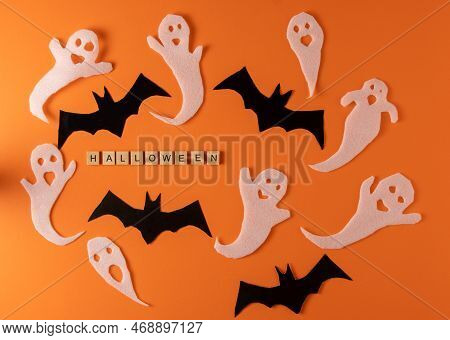 White Ghosts And Bat Craft For Halloween Party. Wrapping Paper Ghost On Orange Background Top View. 