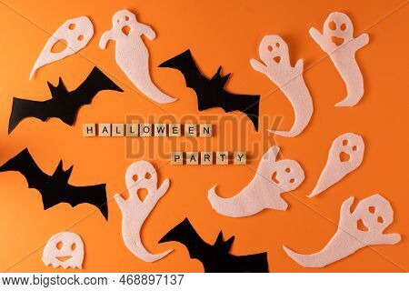 White Ghosts And Bat Craft For Halloween Party. Wrapping Paper Ghost On Orange Background Top View. 