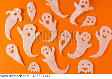 White Ghosts Kids Craft For Halloween. Paper Ghost On Orange Background Top View. A Scary And Funny 