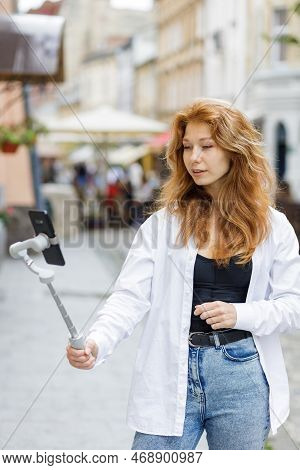 Young Redheaded Beautiful Woman Walking And Using Her Mobile Phone
