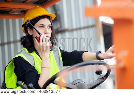 Young Asian Woman Is Foreman Using Radio For Communication While Driving Forklift At Distribution Wa