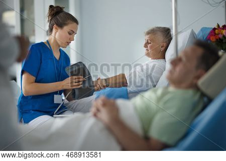 Young Nurse Chcecking Blood Presure To Senior Patient.