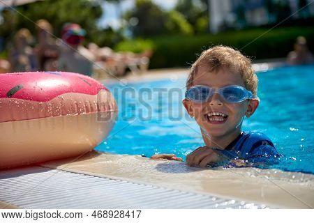 Cheerful Boy In Swimming Glasses Swims In A Summer Pool With An Inflatable Circle. Funny Kid Having 
