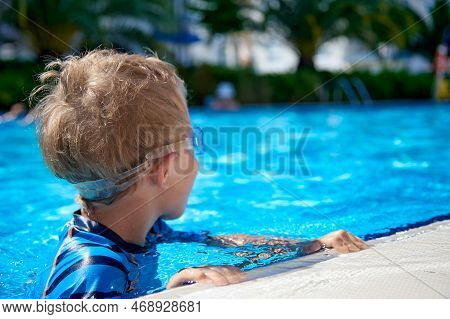 Child Is Swimming In A Clean Outdoor Pool, The Childs Head Above The Water, Turned Away From The Cam