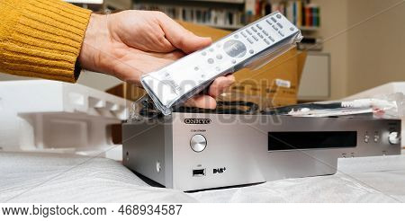 Paris, France - Dec 13, 2022: Pov Male Hand Holding New Covered With Plastic Remote Control Above Ne