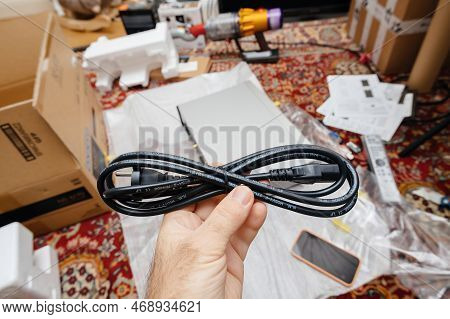 Paris, France - Dec 13, 2022: Pov Male Hand Holding Power Cable After Unboxing New Onkyo Ns-6170 Net