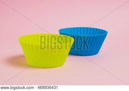 Blue And Yellow Silicone Cupcake Molds On A Pink Paper Background