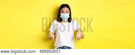 Covid-19, Pandemic And Social Distancing Concept. Amazed Asian Woman In Medical Mask, Showing Advert