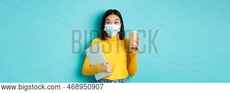 Covid-19, Health Care And Quarantine Concept. Asian Girl Student In Medical Mask Standing With Lapto