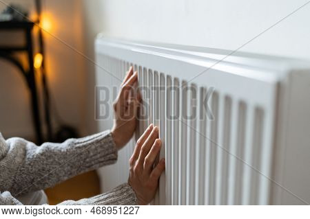 Closeup Of Woman In Woolen Sweater Wants To Keep Warmth In Apartment. Female Puts Hands On Room Cent