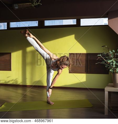 Young Woman Practicing Yoga Doing Adhomukha Utthitahasta Padangushthasana Exercise, Leg Stretch Pose
