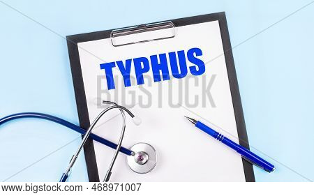 On A Blue Background, A Stethoscope, A Pen And A Tablet With Paper And The Text Typhus. Medical Conc