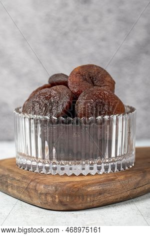 Dried apricots on stone background. Dark dried apricots in a glass bowl. Diet foods. close up