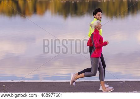 Running Couple While Training Outdoors On Road At River Shore For Durable Marathon Pretty Young Fema