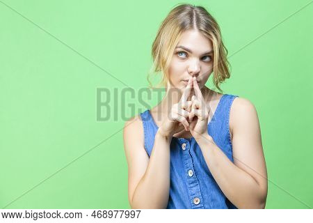 Curious Winsome Caucasian Blond Girl In Blue Dress Posing While Holding Hands In Front Of Face With