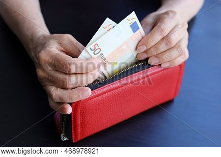 Euro Banknotes In Red Wallet In Wrinkled Hands Of Elderly Woman. Concept Of Pension Payments And Ass