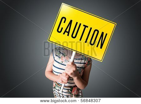 Young lady standing and holding a yellow caution sign in front of her head