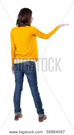 Back view of Beautiful business woman in yellow pulover looking at wall and Holds a hand up.  young brunette girl standing. Rear view people. Isolated over white background. 