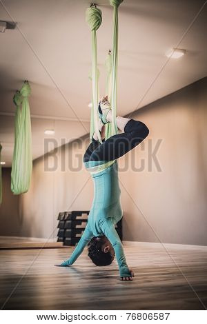 Young woman performing antigravity yoga exercise 