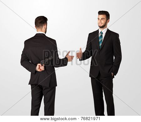 Two opposing businessman shake hands, one of them hiding a weapon behind his back