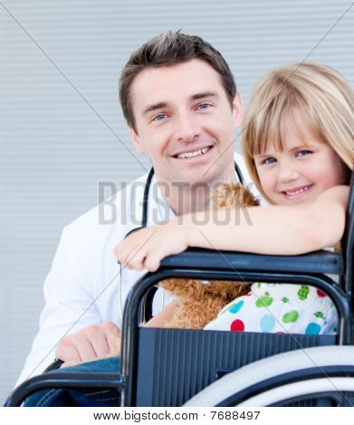 Onun doktor ile bir tekerlekli sandalye üzerinde oturan sevimli kız