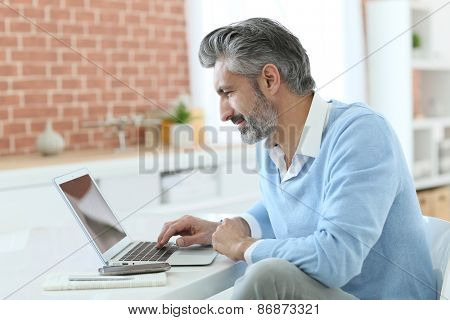 Trendy mature man working from home with laptop