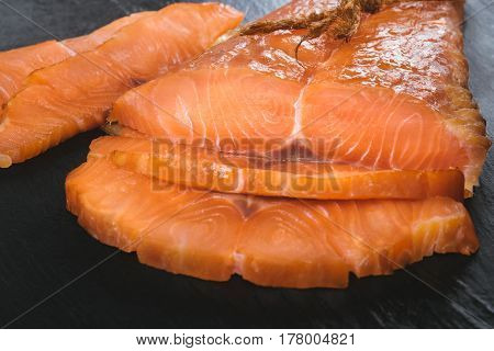 Smoked salmon fish on a slate board. Cutted slices of smoked salmon. Tasty smoked fillet of red fish