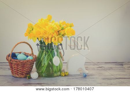 Easter eggs hunt - white rabbit, basket with painted eggs and daffodils bouquet, retro toned