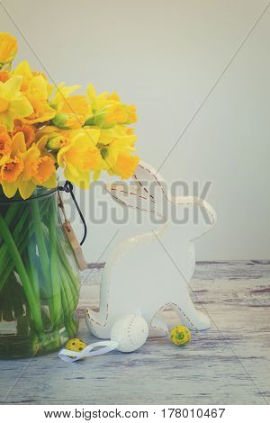 Easter eggs hunt - white rabbit with eggs and daffodils bouquet, retro toned