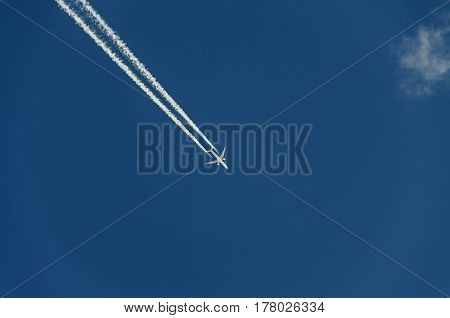 Airplane With Reaction Trail Flying Over Blue Sky With Clouds, Close Up