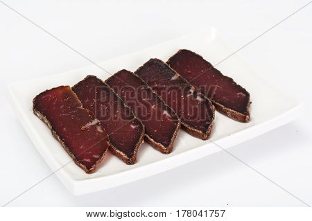 Dried beef basturma, chopped on white. Studio Photo