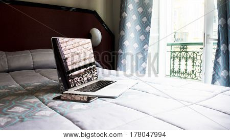 a laptop on the bed in the room in Paris writing fashion blog in Paris working at home or wathing movie on the bed. A silver laptop located on the bed near the window