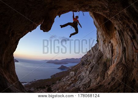 Female rock climber gripping handhold on ceiling in cave