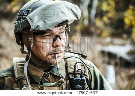 Norwegian Armed Forces Special Command FSK soldier smoking cigarette closeup portrait. Radio and headset are on