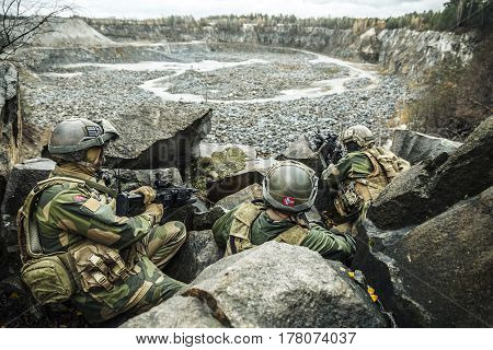 Patrol of norwegian Rapid reaction special forces FSK soldiers in field uniforms in ambush among the rocks guarding perimeter waiting enemy