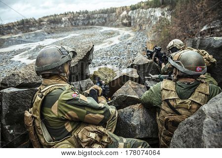 Patrol of norwegian Rapid reaction special forces FSK soldiers in field uniforms in ambush among the rocks guarding perimeter waiting enemy
