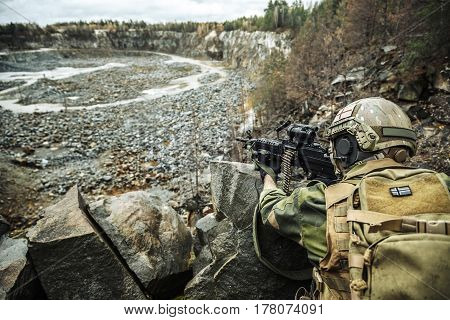 Norwegian Rapid reaction special forces FSK soldier in field uniforms in ambush among the rocks guarding perimeter waiting enemy