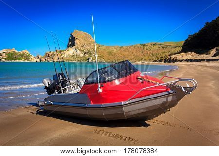 landscape with the red motor boat and the sandy beach, location - Castlepoint lighthouse, North Island, New Zealand