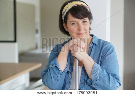 Cheerful overweigth woman having fun sweeping the floor